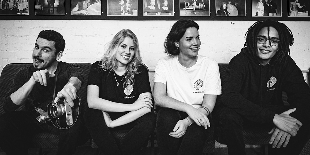 A black & white photo of 4 young people sitting on a couch