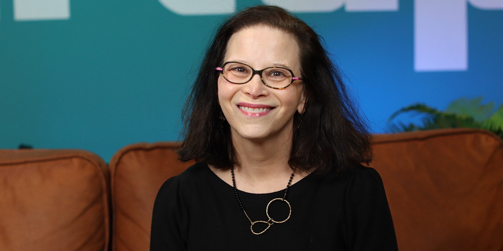 A woman sitting on a sofa, posing for a photo